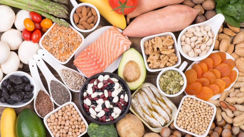 연어, 아보카도, 견과류, 콩류 등 붓기를 완화하는 음식들이 한 상에 놓인 장면으로, 붓기 빼는 음식의 균형 잡힌 식단을 표현함 A healthy food assortment including salmon, avocado, nuts, and beans arranged together to represent anti-swelling foods and a balanced diet