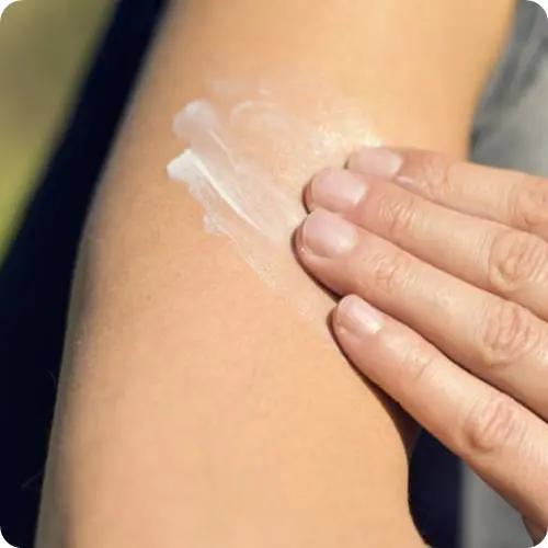 햇빛에 노출된 팔 피부에 선크림을 고르게 바르는 손의 근접 장면. 자외선 차단을 위해 부드럽게 크림을 펴 바르고 있으며, 자연광 아래에서 피부 보호를 실천하는 모습이 담겨 있다. (Close-up of a hand gently applying sunscreen on the forearm under natural sunlight, showing even coverage for UV protection and healthy skin care routine.)