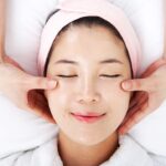 눈을 감은 채 얼굴 마사지를 받는 여성의 모습으로, 얼굴 붓기 완화와 림프 순환 개선을 표현한 이미지 A woman receiving a facial massage with eyes closed, representing facial puffiness relief and improved lymph circulation