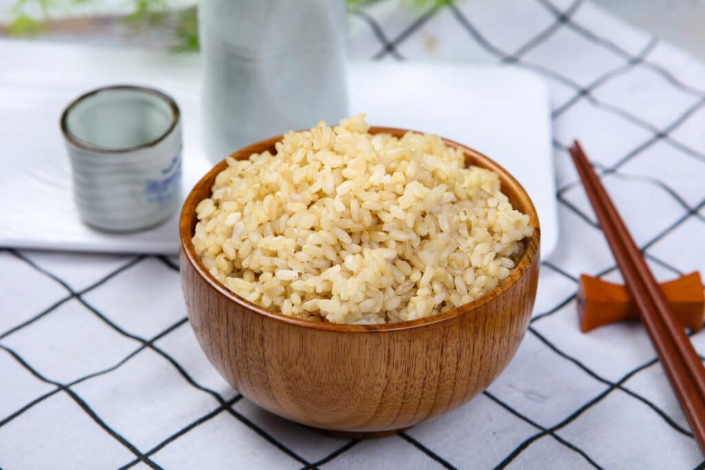 나무 그릇에 소복이 담긴 현미밥. 당뇨에 안좋은 흰쌀밥 대신 식이섬유가 풍부한 현미밥을 섭취하면 포만감이 오래가고 혈당 상승 속도를 늦출 수 있습니다.